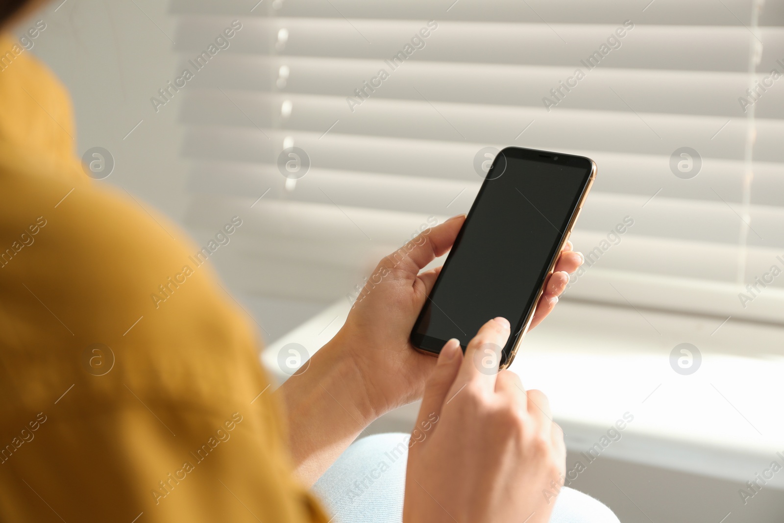 Photo of Young woman using modern smartphone indoors, closeup