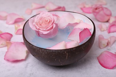 Photo of Beautiful composition with bowl of water and rose petals on light table, closeup. Spa treatment