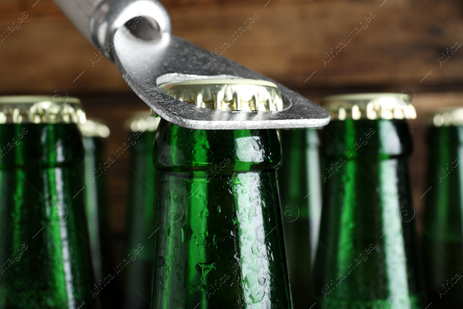 Photo of Opening bottle of beer on wooden background, closeup