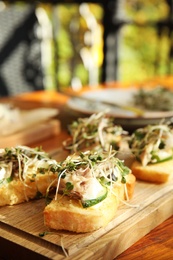 Photo of Delicious bruschettas with fish on wooden table