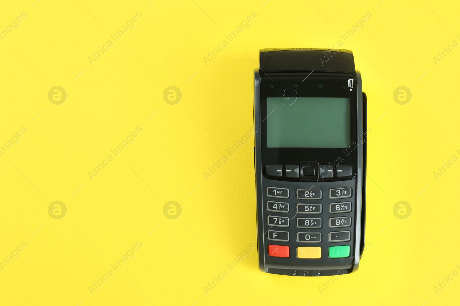 Photo of New modern payment terminal on yellow background, top view. Space for text