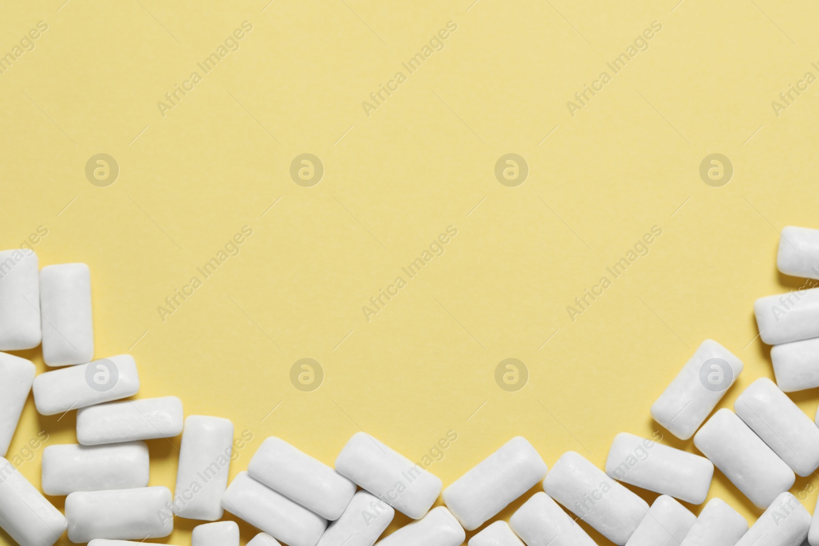 Photo of Tasty white chewing gums on yellow background, flat lay. Space for text