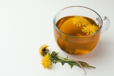 Photo of Delicious fresh tea and beautiful dandelion flowers on white background. Space for text