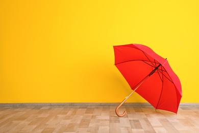 Beautiful open umbrella on floor near color wall with space for design