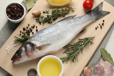 Photo of Tasty sea bass fish and spices on wooden table, flat lay