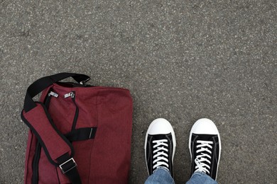 Man with bag standing on asphalt, top view. Space for text