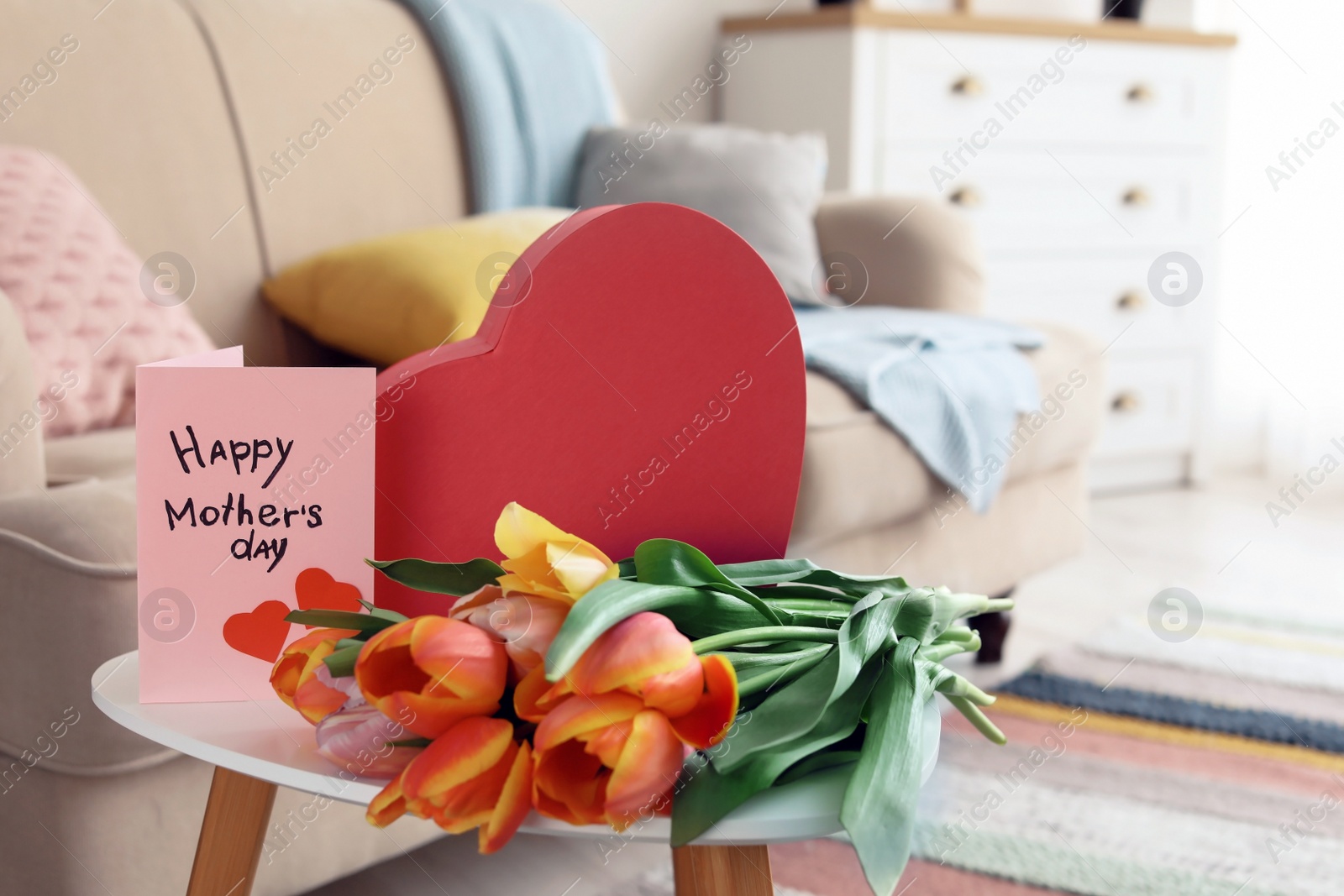 Photo of Gift box, tulips and greeting card for Mother's Day on table indoors