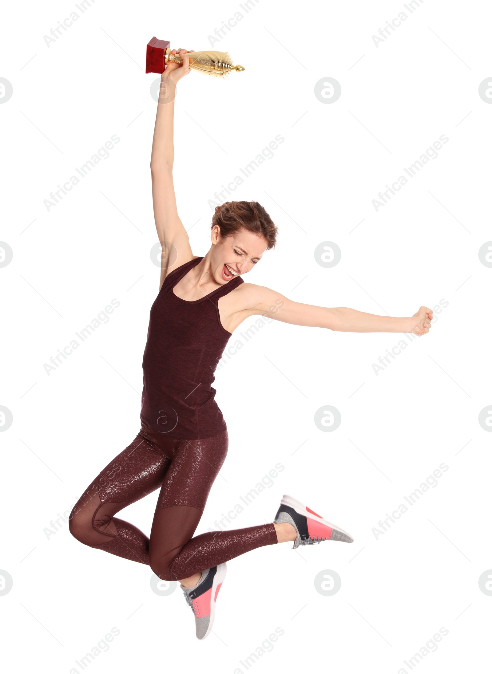 Photo of Happy young sportswoman with gold trophy cup jumping on white background