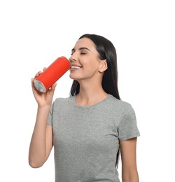 Beautiful happy woman drinking from red beverage can on white background