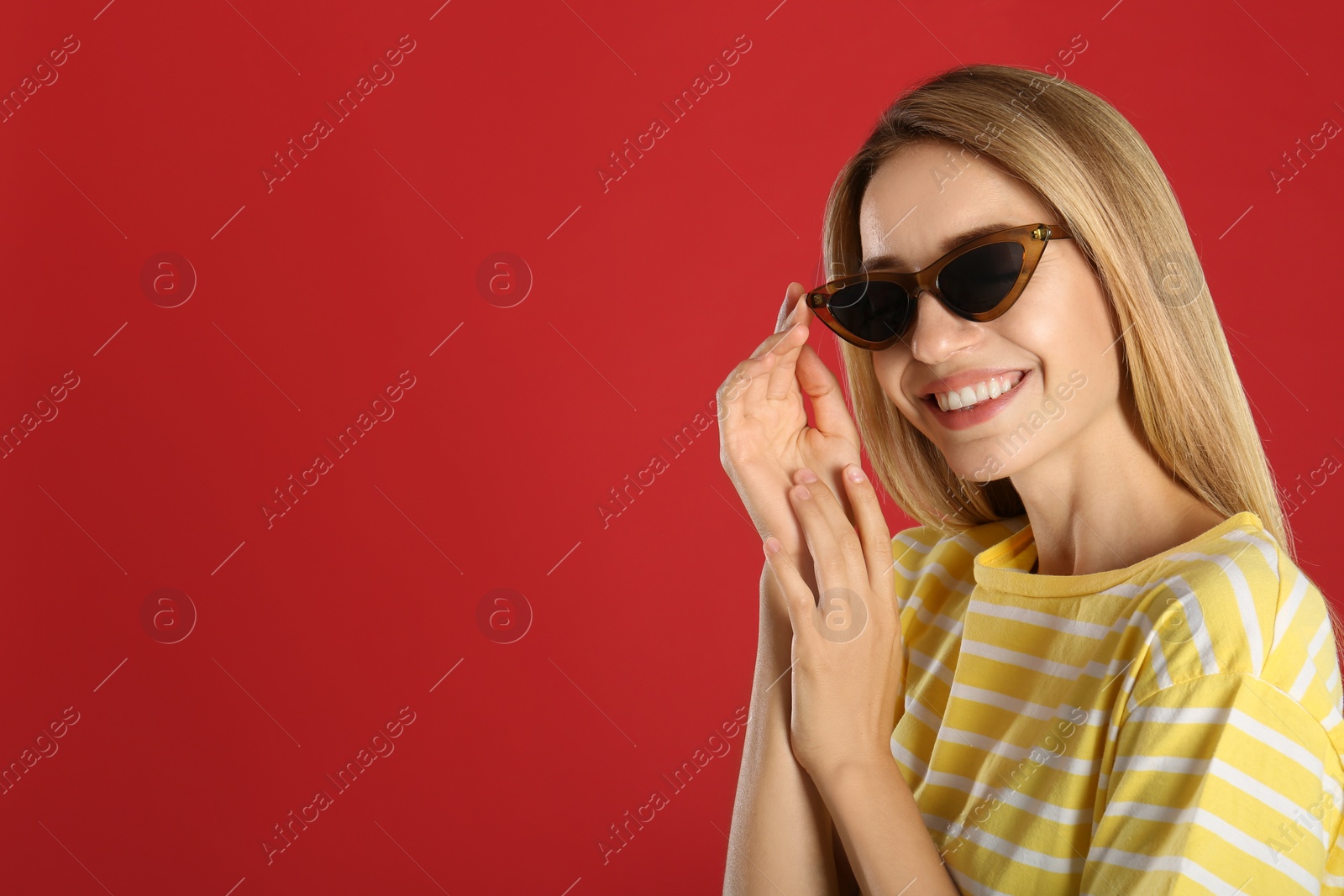 Photo of Beautiful woman in stylish sunglasses on red background. Space for text