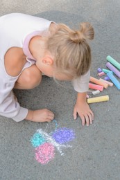 Little child drawing butterfly with chalk on asphalt