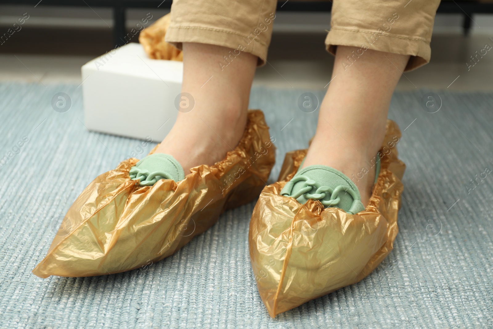 Photo of Woman wearing shoe covers onto her mules indoors, closeup