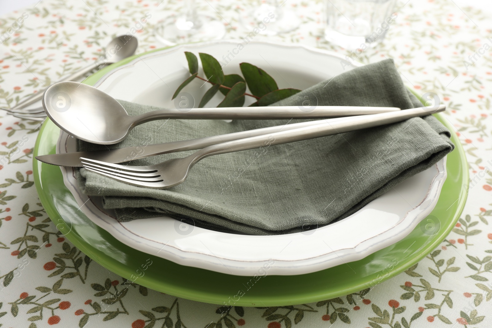 Photo of Stylish setting with cutlery, plates, napkin and floral decor on table, closeup