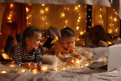 Photo of Kids with laptop in decorated play tent at home