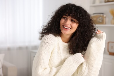 Photo of Happy young woman in stylish white sweater indoors, space for text