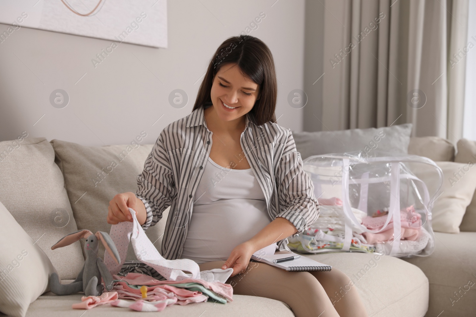 Photo of Pregnant woman packing bag for maternity hospital at home