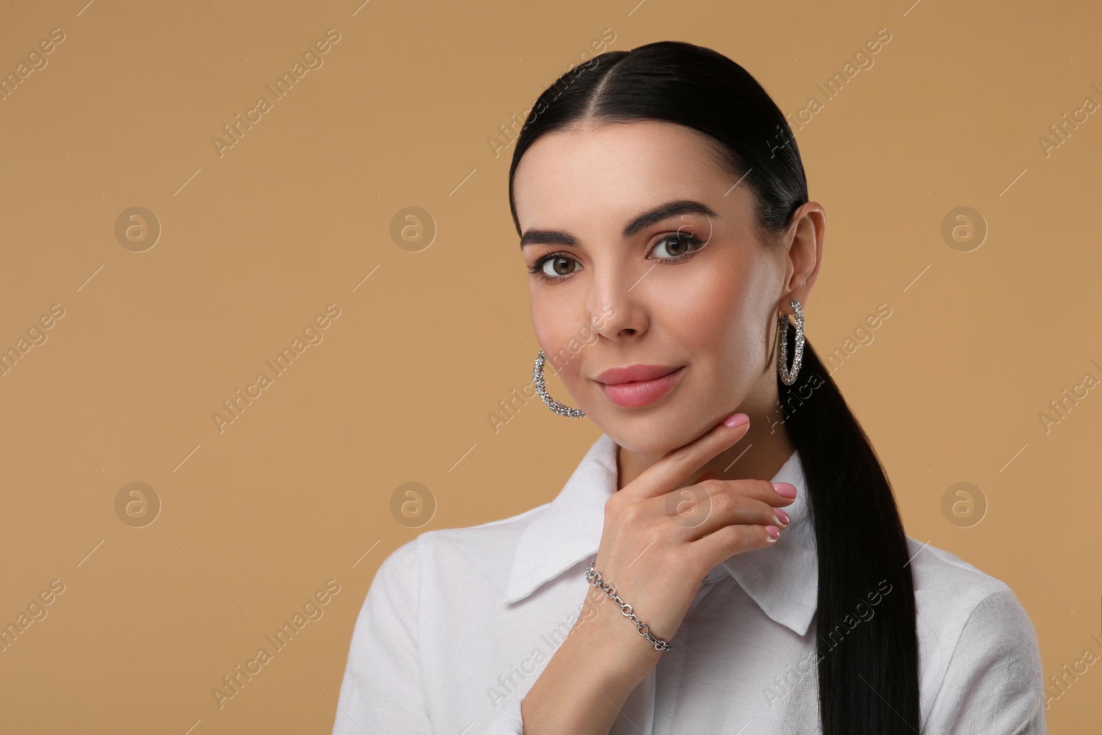 Photo of Young woman with elegant jewelry on beige background. Space for text