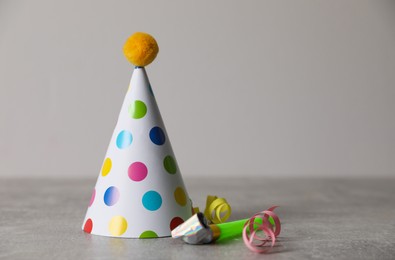 Photo of Birthday party hat, horn and serpentine streamers on grey table