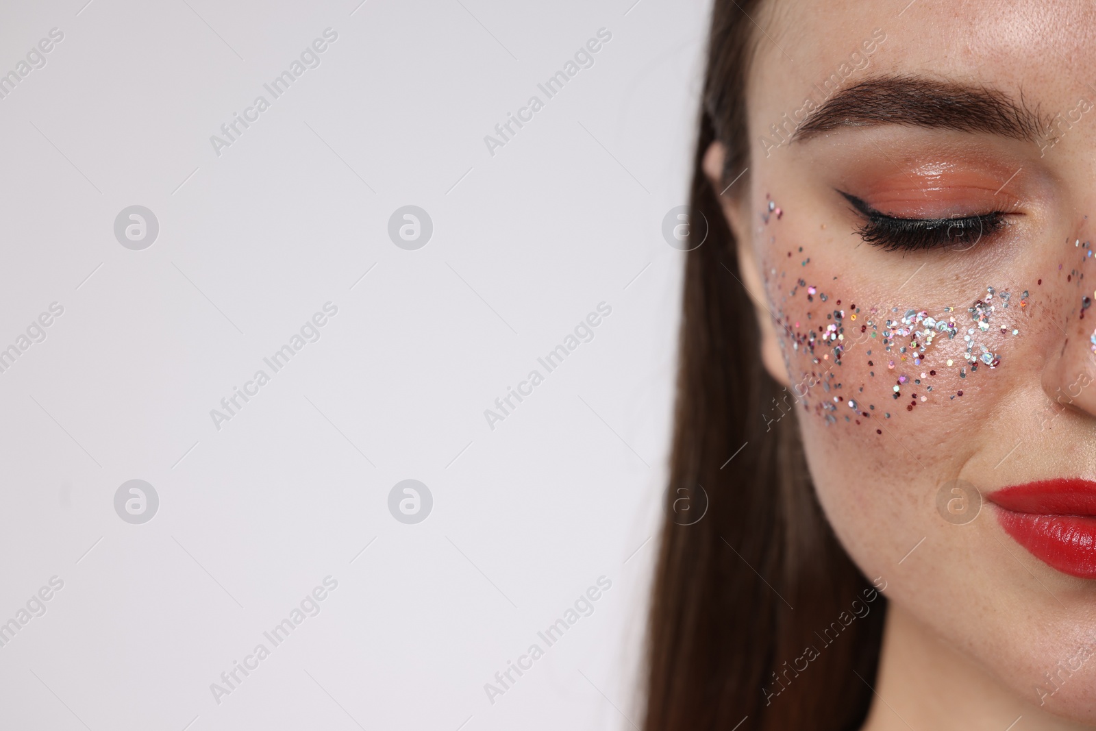 Photo of Beautiful woman with glitter freckles on light background, closeup. Space for text