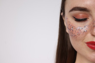 Photo of Beautiful woman with glitter freckles on light background, closeup. Space for text