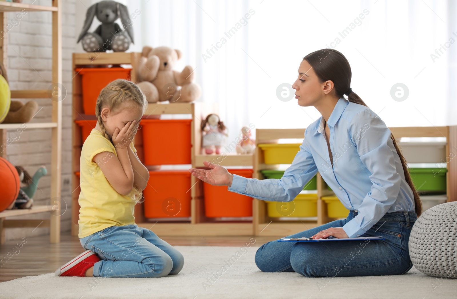 Photo of Child psychotherapist working with little girl in office