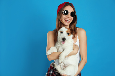 Photo of Young woman with her cute Jack Russell Terrier on light blue background. Lovely pet