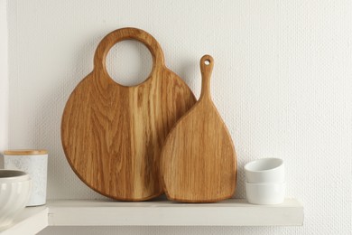 Wooden cutting boards, container and bowls on white shelf