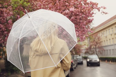 Photo of Young woman with umbrella on spring day, back view. Space for text