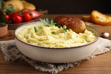 Bowl of tasty mashed potatoes with parsley, black pepper and cutlet served on wooden table, closeup
