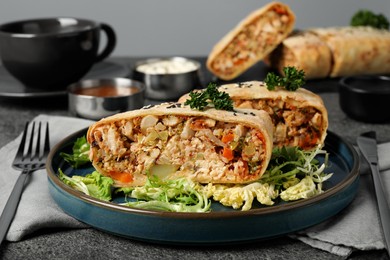 Photo of Pieces of delicious strudel with chicken and vegetables served on grey textured table, closeup