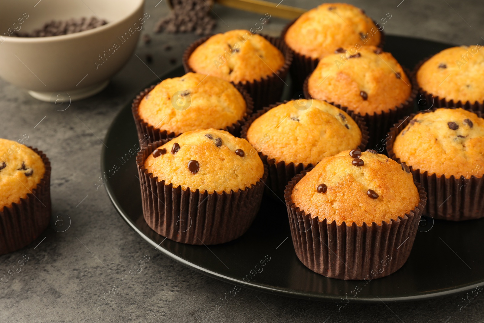 Photo of Delicious freshly baked muffins with chocolate chips on gray table, closeup