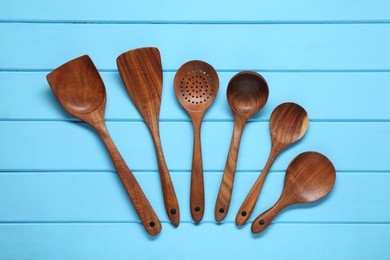 Set of wooden kitchen utensils on light blue table, flat lay