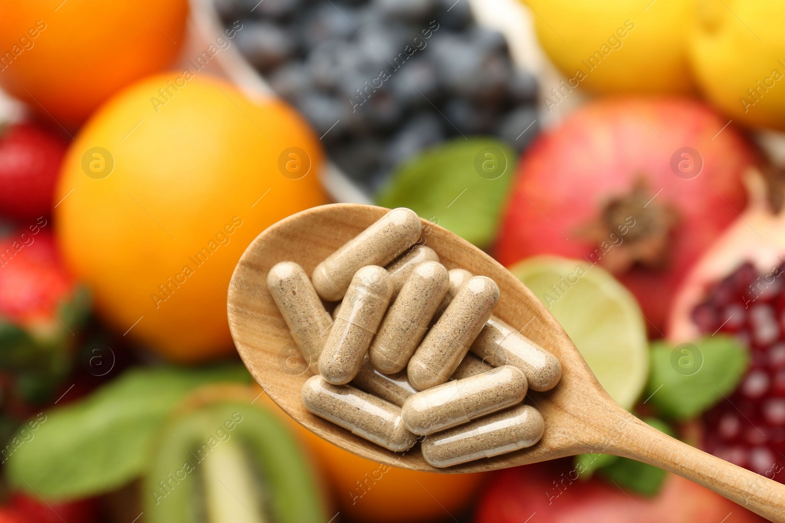 Photo of Vitamin pills in spoon over fresh fruits, top view