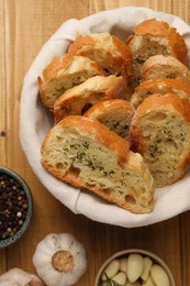 Photo of Tasty baguette with garlic and other spices on wooden table, flat lay