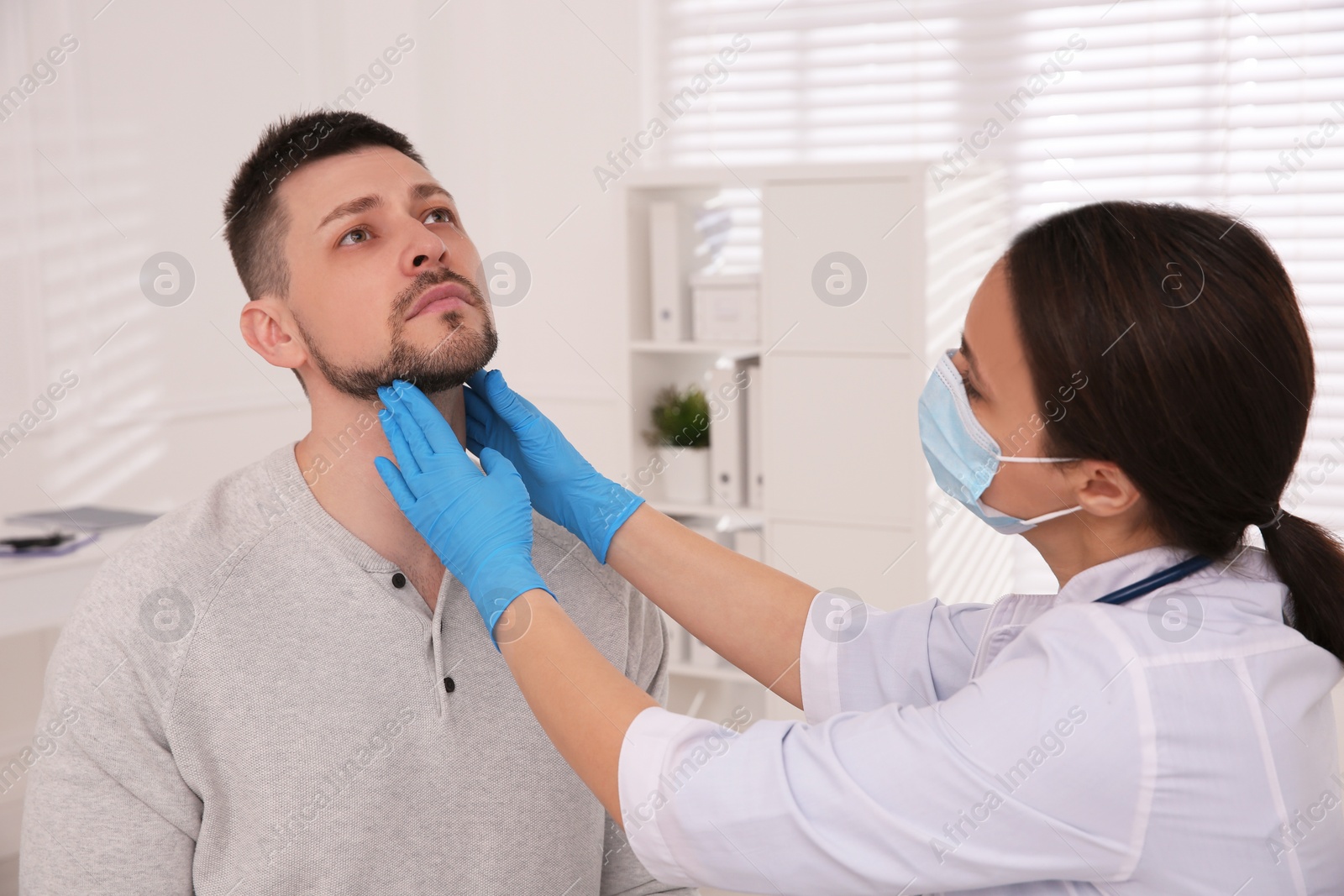 Photo of Doctor examining thyroid gland of patient in hospital