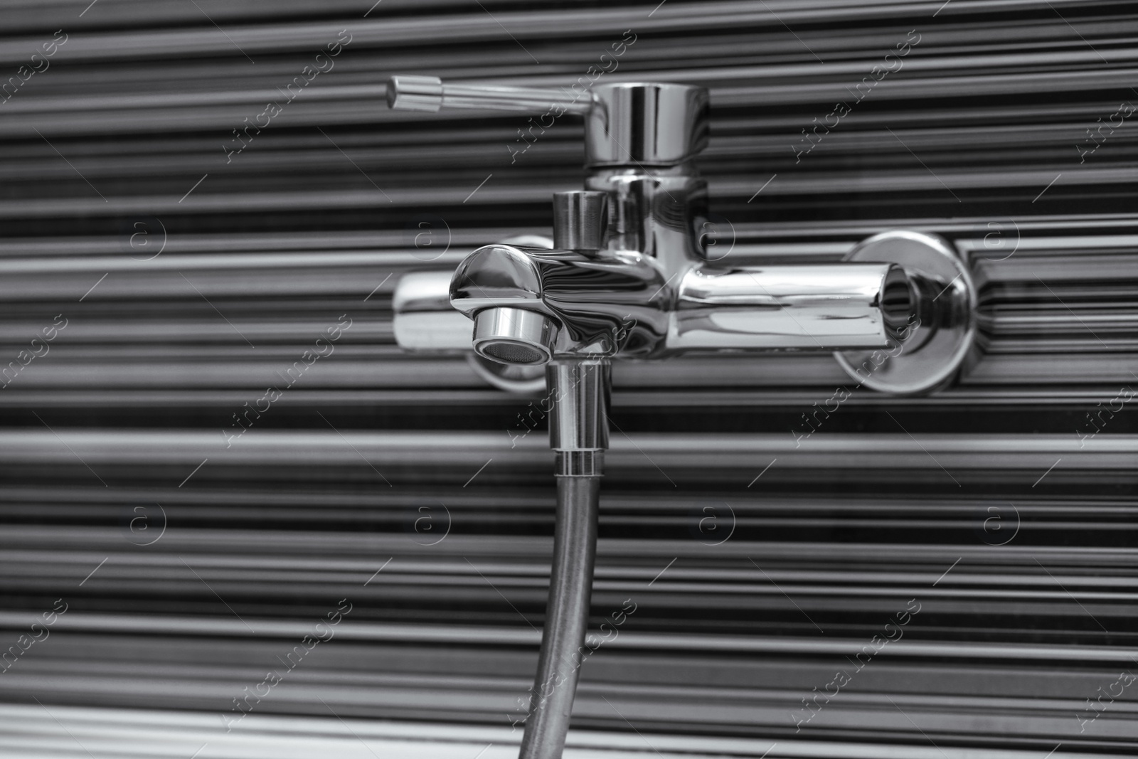 Photo of Shiny bath water tap installed on black and white wall