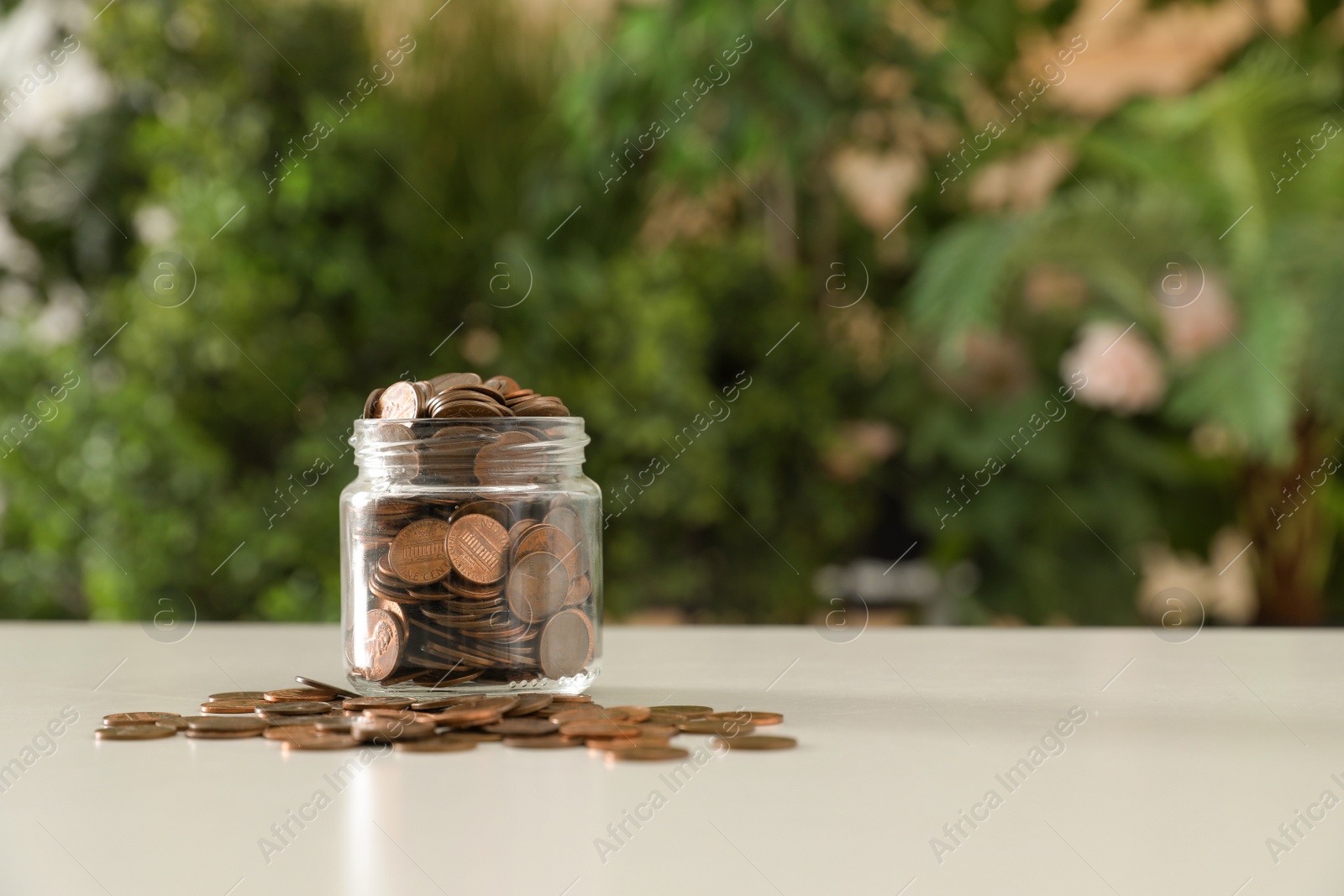 Photo of Donation jar with coins on table against blurred background. Space for text