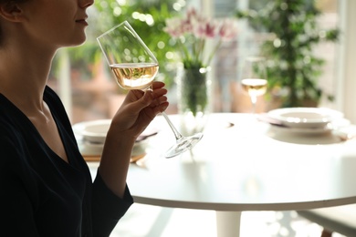 Photo of Woman with glass of wine in restaurant, closeup. Space for text