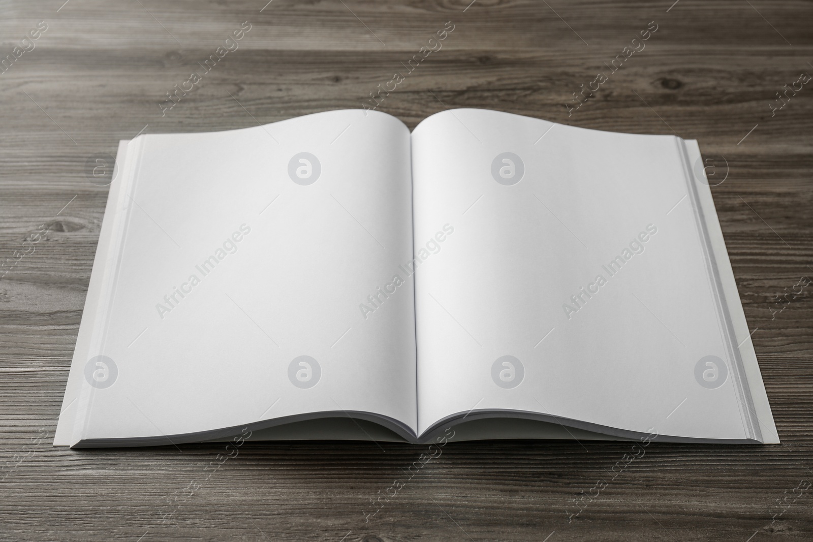 Photo of Open blank paper brochure on wooden table. Mockup for design