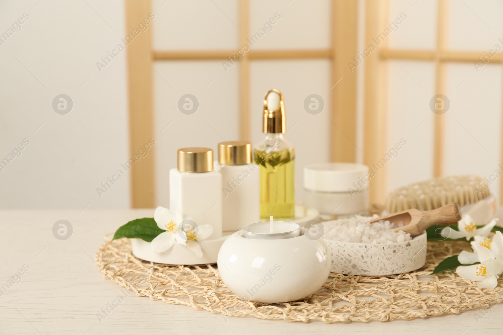 Photo of Composition with beautiful jasmine flowers and skin care products on white wooden table indoors