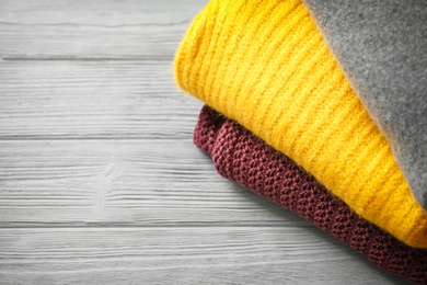 Photo of Stack of warm knitted clothes on wooden table