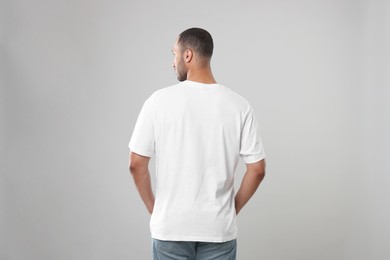 Man wearing white t-shirt on gray background, back view