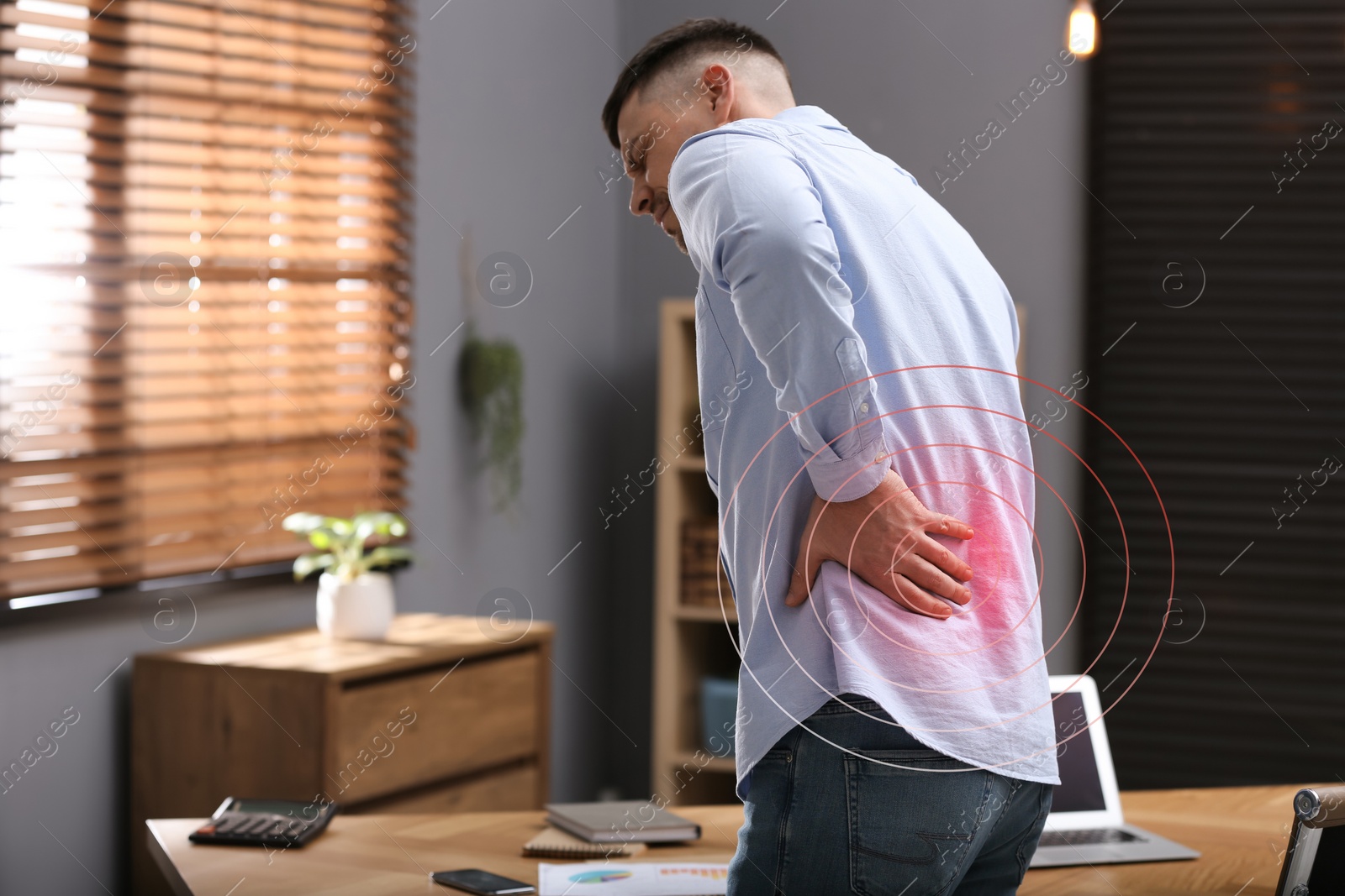 Image of Man suffering from back pain in office. Symptom of poor posture