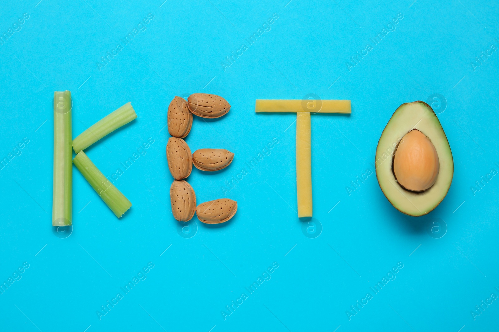 Photo of Word Keto made with different products on light blue background, flat lay