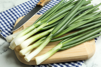 Fresh green spring onions on wooden board, closeup