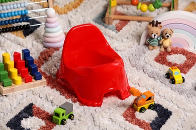 Red baby potty and toys on carpet. Toilet training