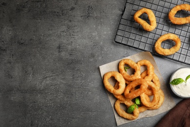 Photo of Fried onion rings served on grey table, flat lay. Space for text