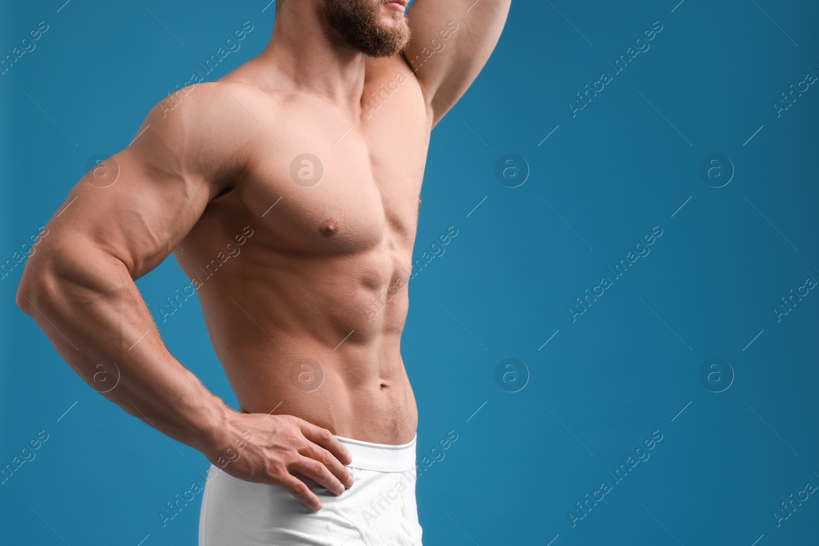 Photo of Muscular man showing abs on light blue background, closeup and space for text. Sexy body