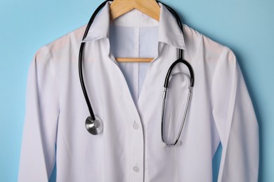 Photo of Medical uniform and stethoscope on light blue background