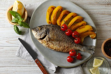 Photo of Delicious roasted dorado fish served with vegetables on wooden table, flat lay